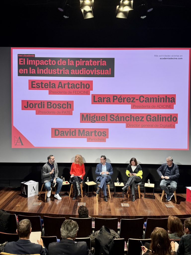 escenario de la jornada de debate de pirateria con los 5 participantes sentados