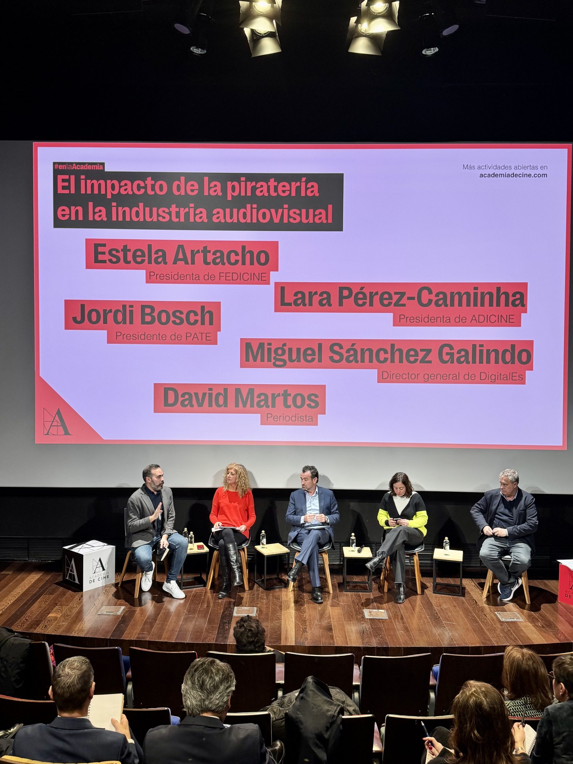 escenario de la jornada de debate de pirateria con los 5 participantes sentados